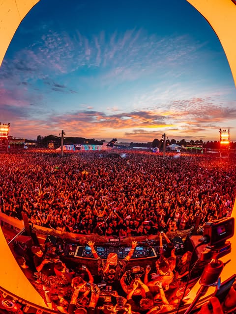 Multidão em festival ao pôr do sol vista da cabine de DJ